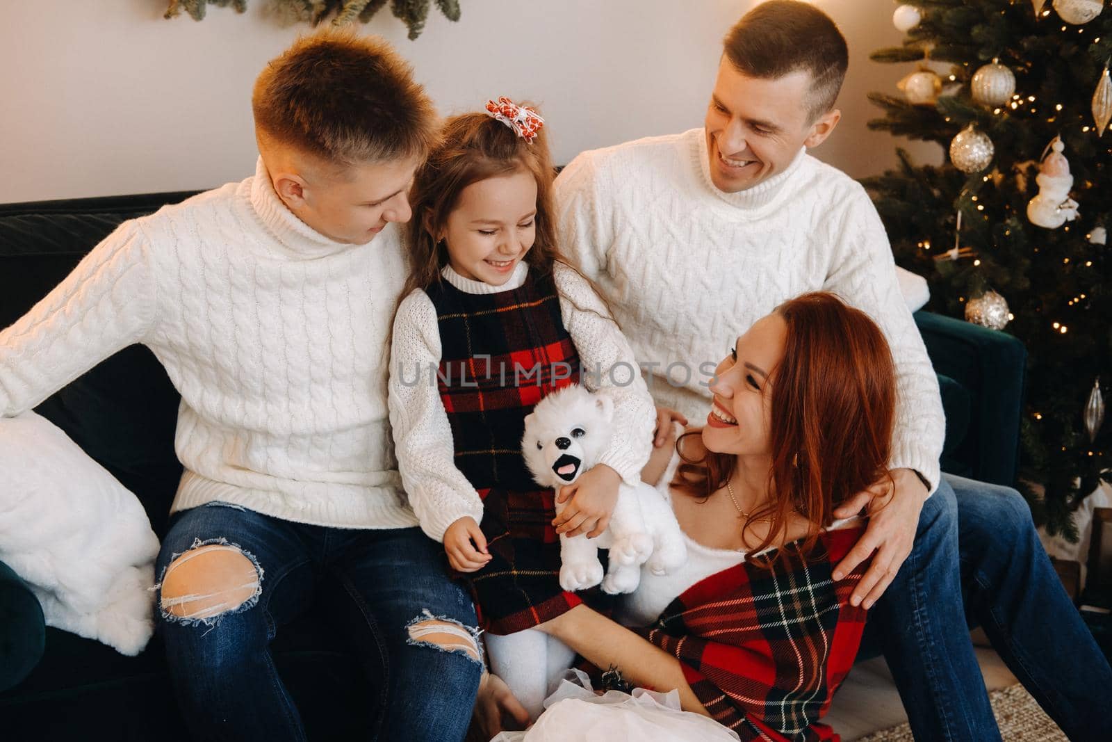 Close-up portrait of a happy family sitting on a sofa near a Christmas tree celebrating a holiday.