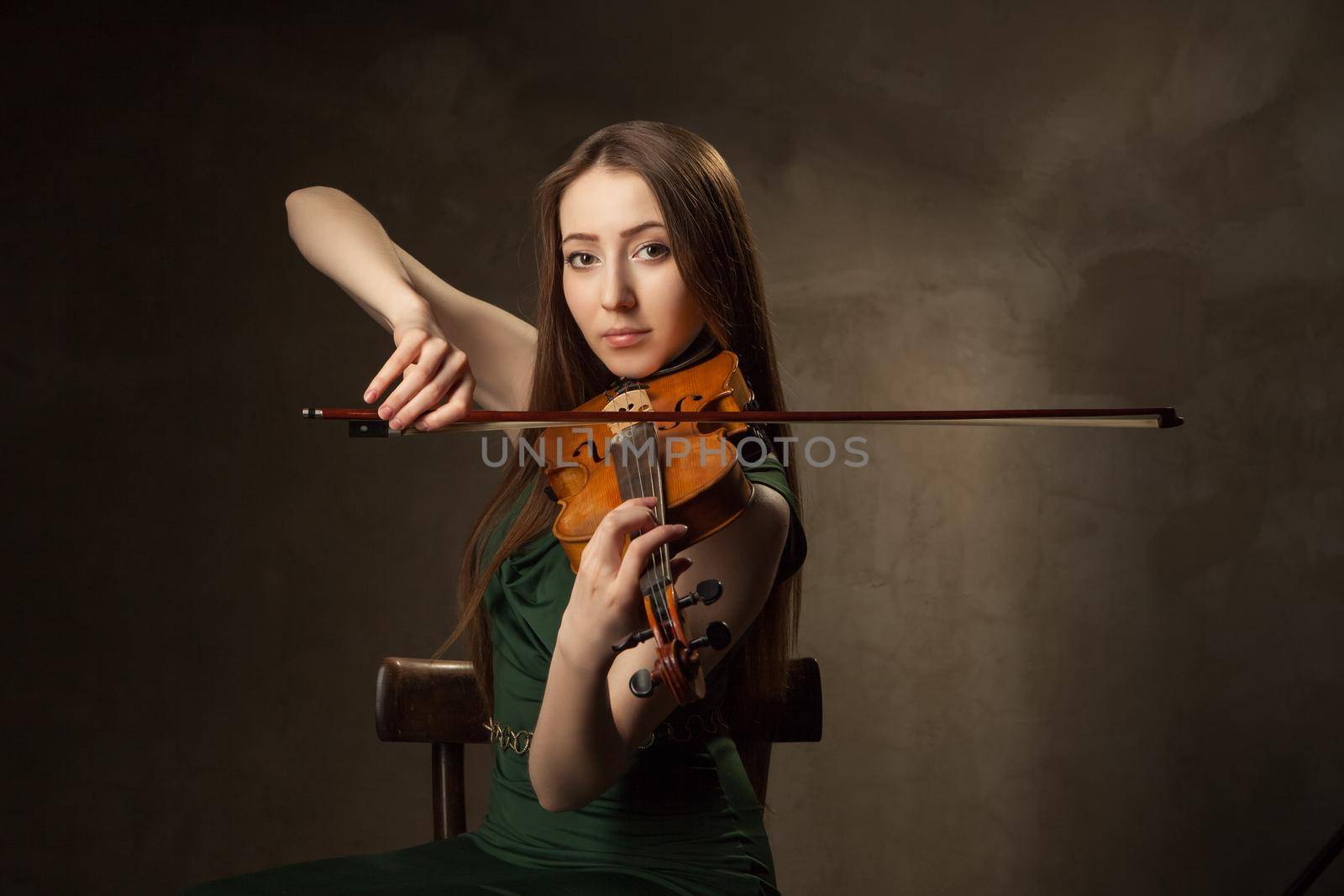 Beautiful young woman playing violin over black background