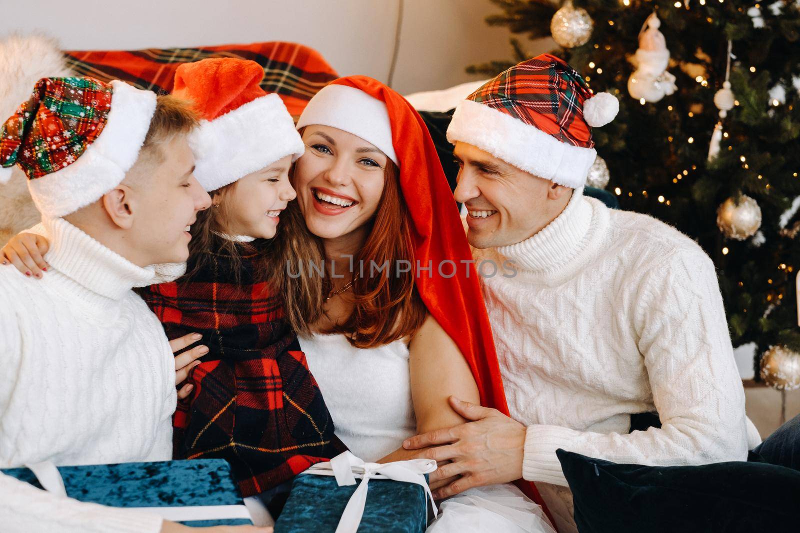 Close-up portrait of a happy family sitting on a sofa near a Christmas tree celebrating a holiday by Lobachad