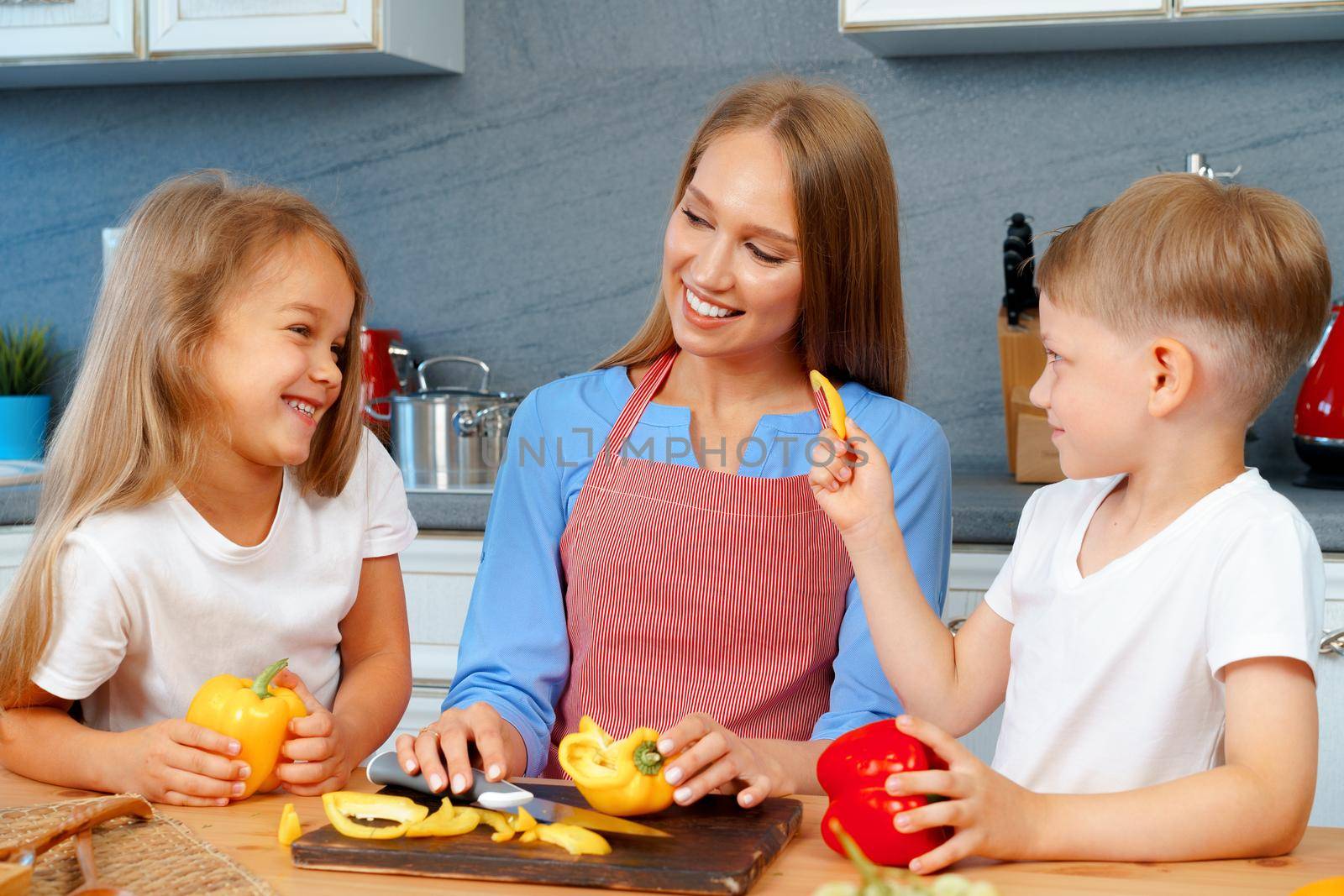 Young mother cooking with her children in kitchen