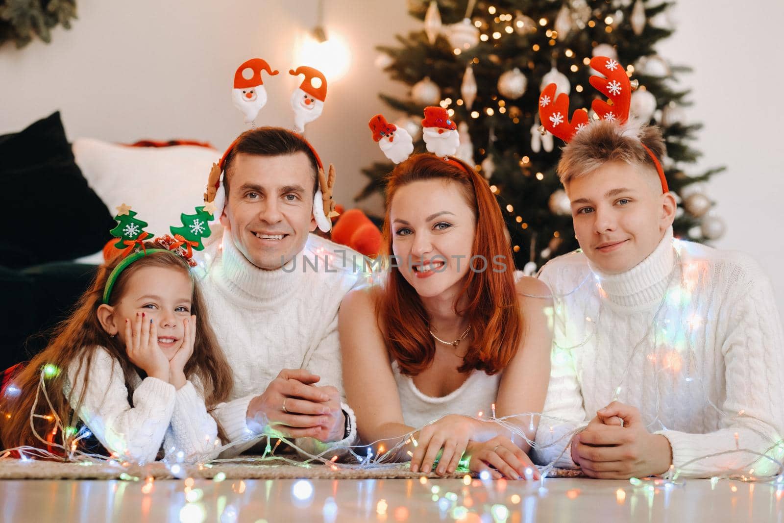 Close-up portrait of a happy family lying near a Christmas tree celebrating a holiday.