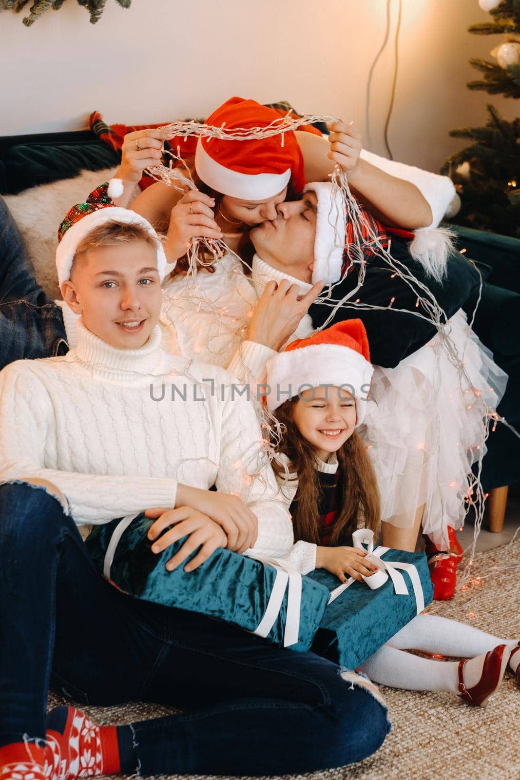 Close-up portrait of a happy family sitting on a sofa near a Christmas tree celebrating a holiday.