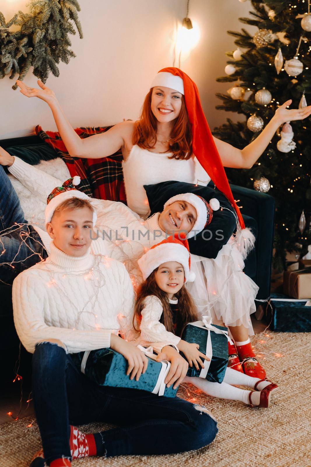 Close-up portrait of a happy family sitting on a sofa near a Christmas tree celebrating a holiday.