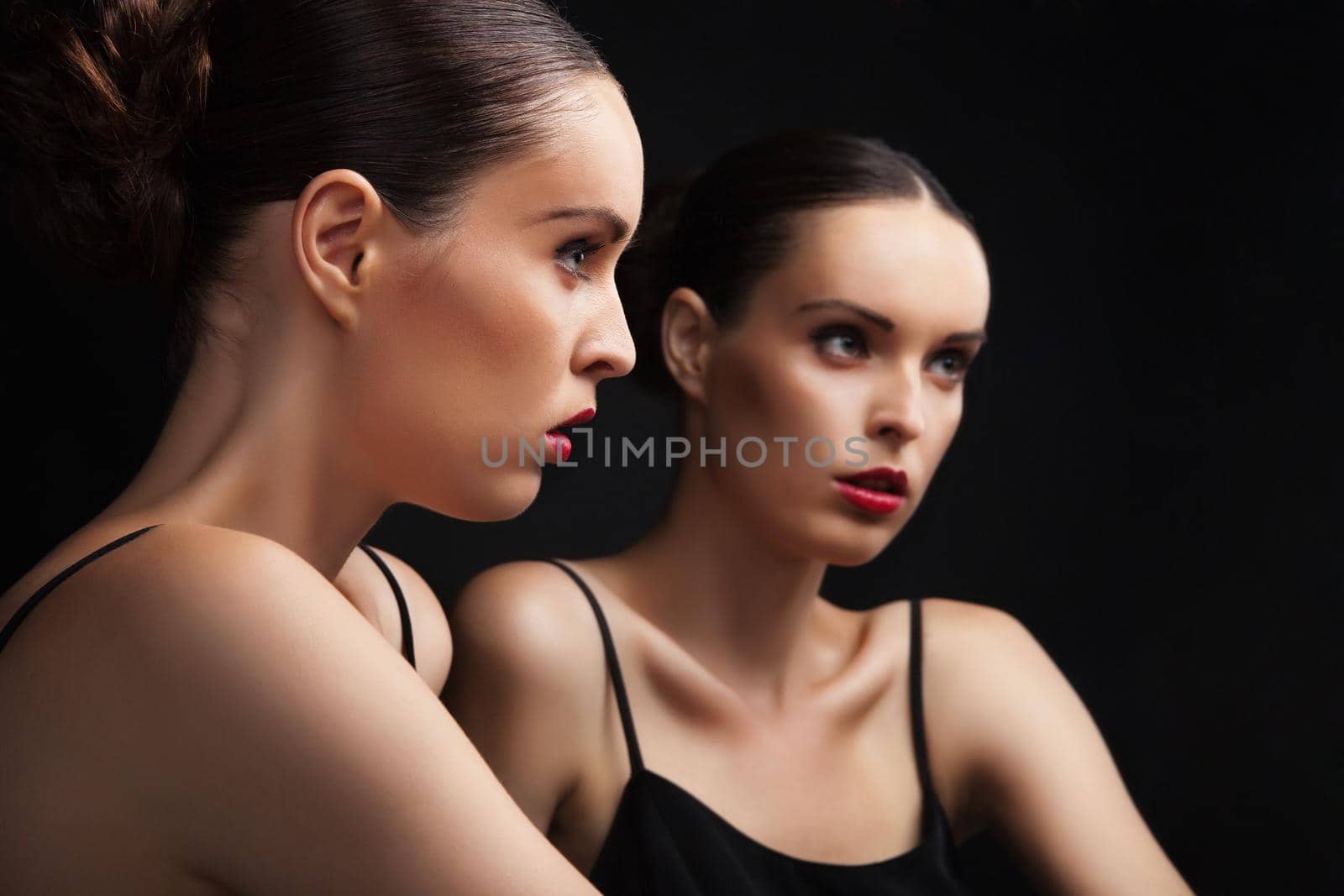 Beautiful sexy young woman near a mirror over black background