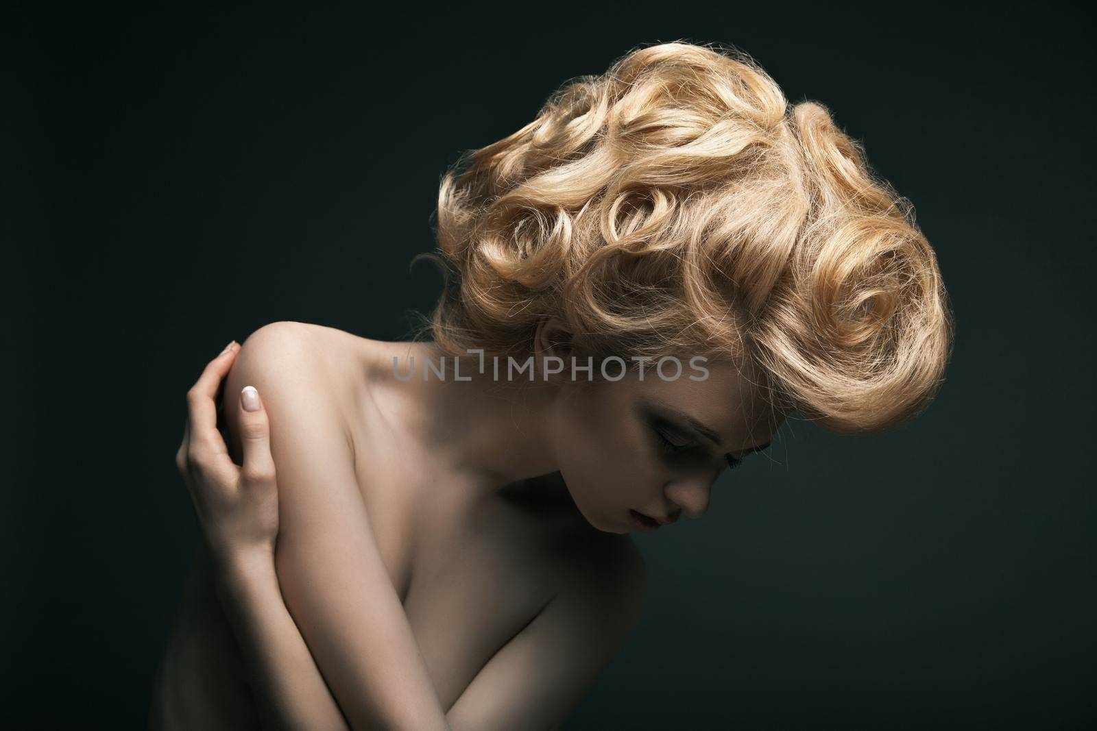 Beautiful high fashion female model with abstract hair style behind the table