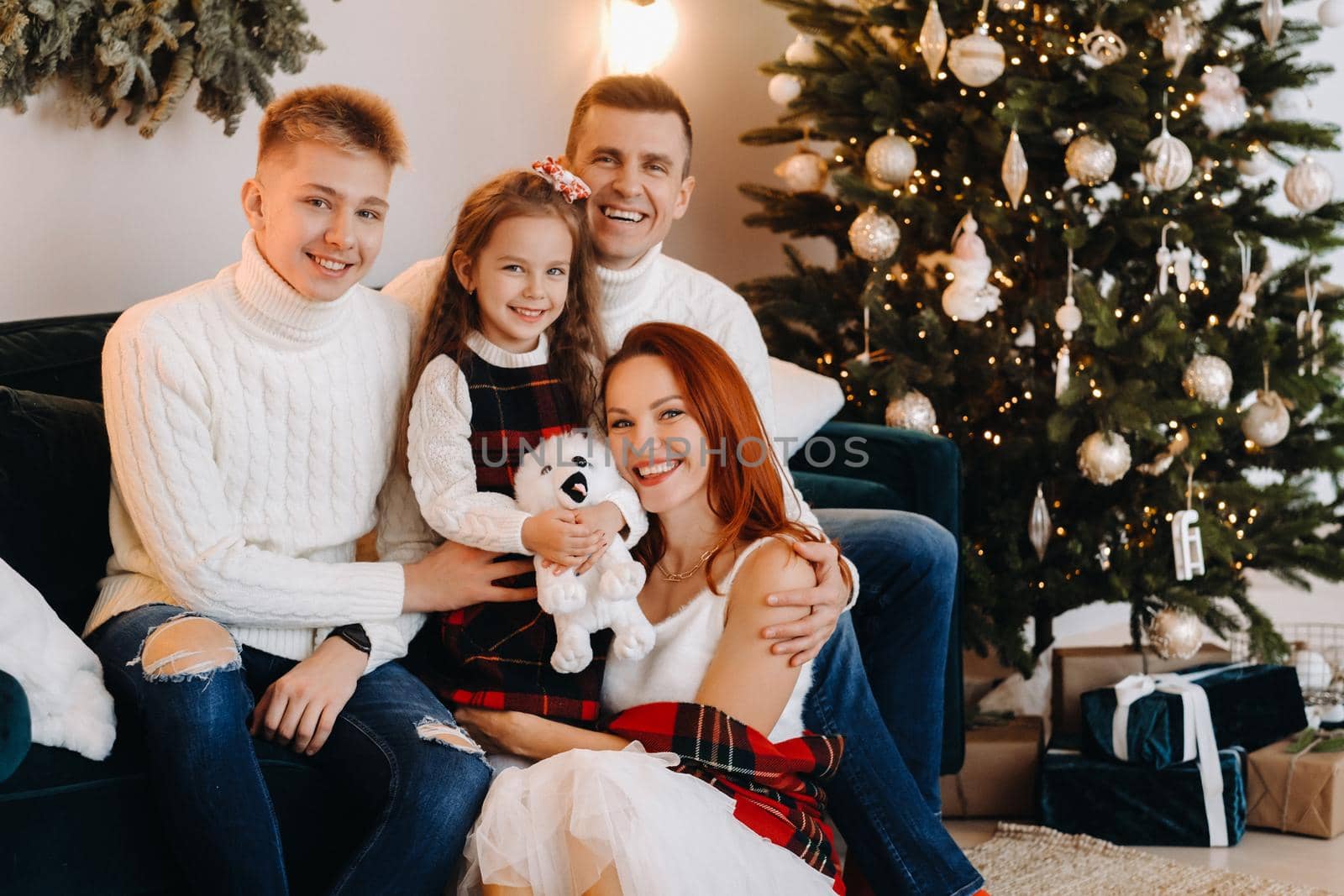 Close-up portrait of a happy family sitting on a sofa near a Christmas tree celebrating a holiday by Lobachad