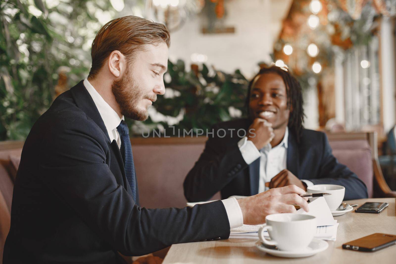 African man. Guy in a black suit. Mixed people have a metting at the cafe.