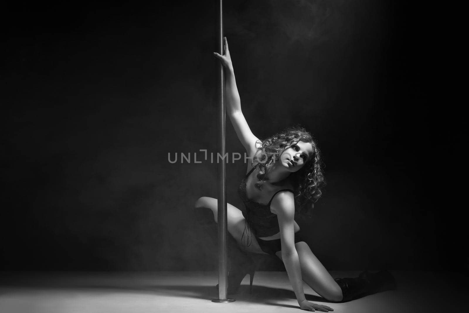Young slim pole dance woman exercising over dark by Julenochek