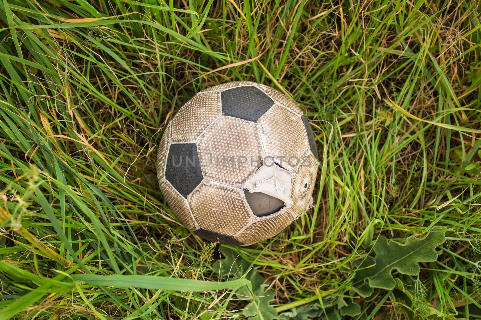 Old Soccer ball on the green grass, top view.