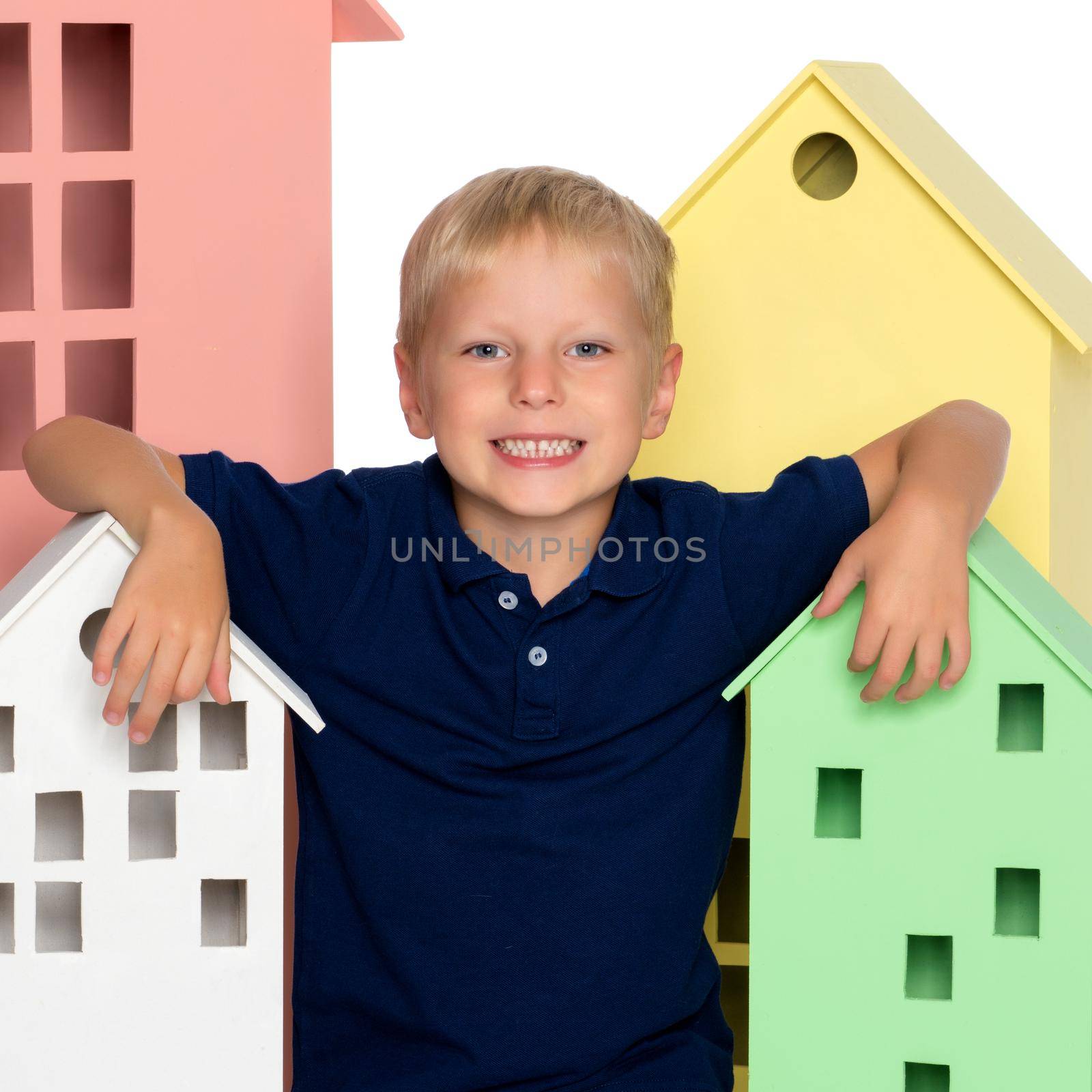 A little boy is playing with colorful houses. The concept of family happiness, the development of the child in kindergarten or in the family. Isolated on white background.