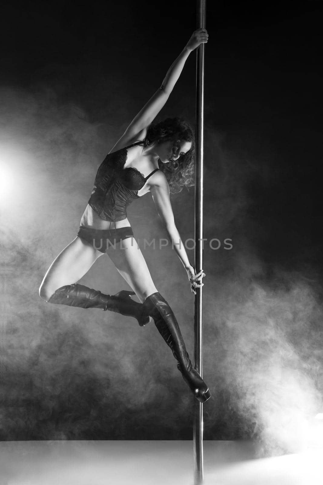 Young slim pole dance woman exercising over dark background