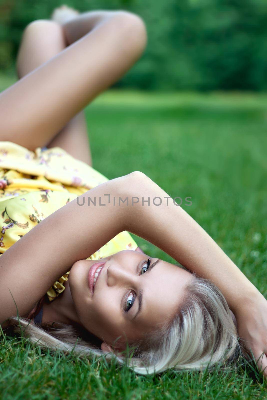 Beautiful smiling young lady laying on the grass by Julenochek