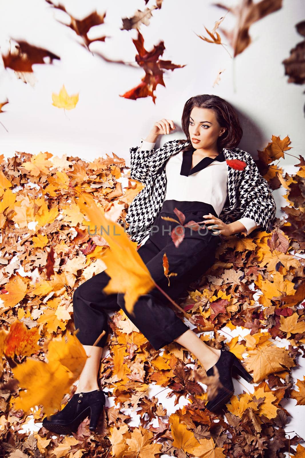 Young brunette woman portrait in lying autumn leaves