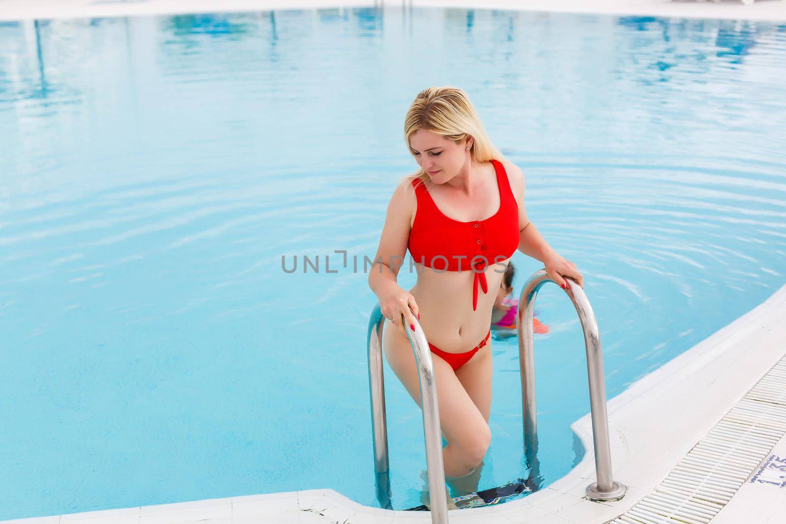 Woman enjoying vacation holidays at luxurious beachfront hotel resort with swimming pool and tropical lansdcape near the beach.