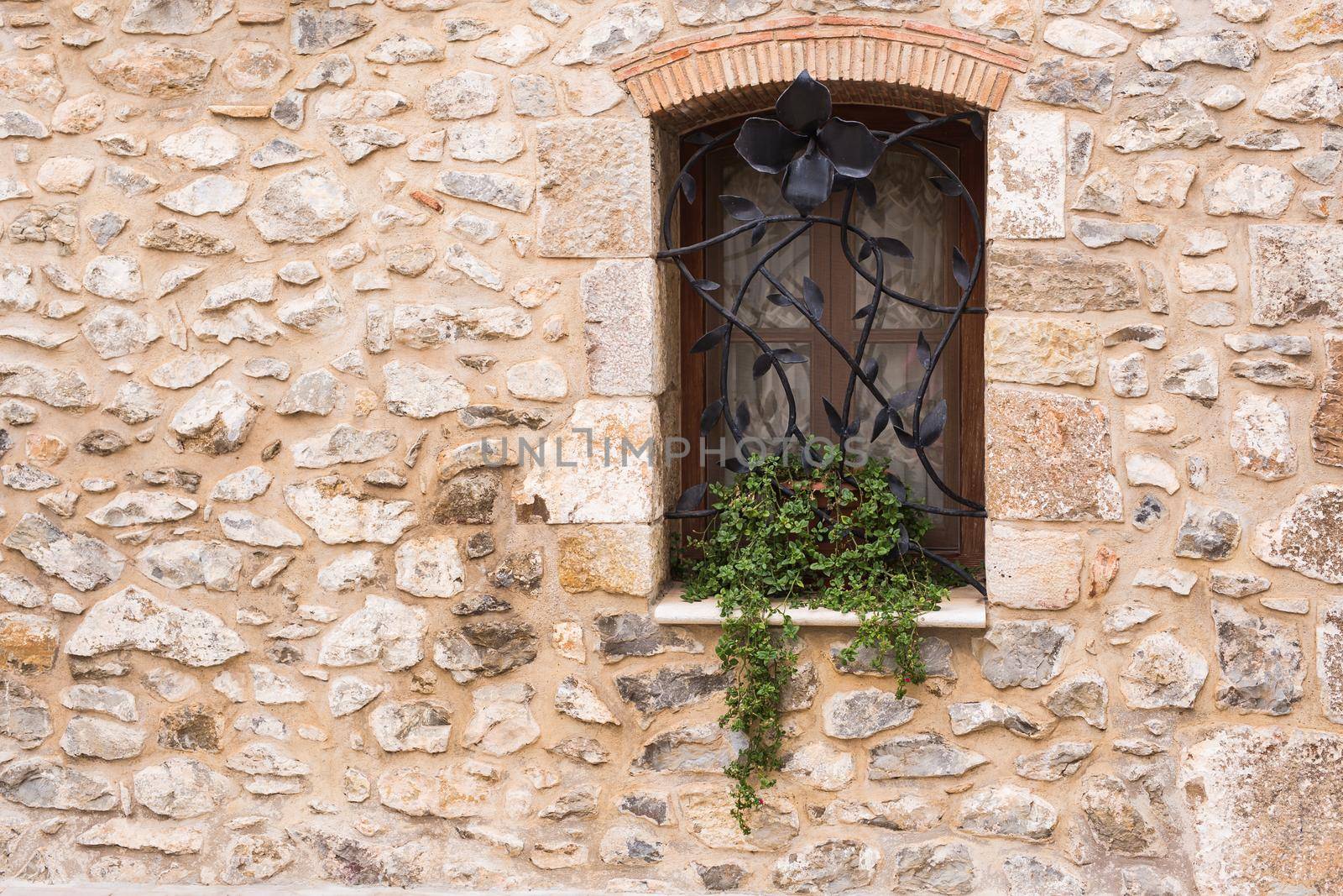 Design, architecture and exterior concept - Beautiful wrought-iron grille in the window on stone wall.