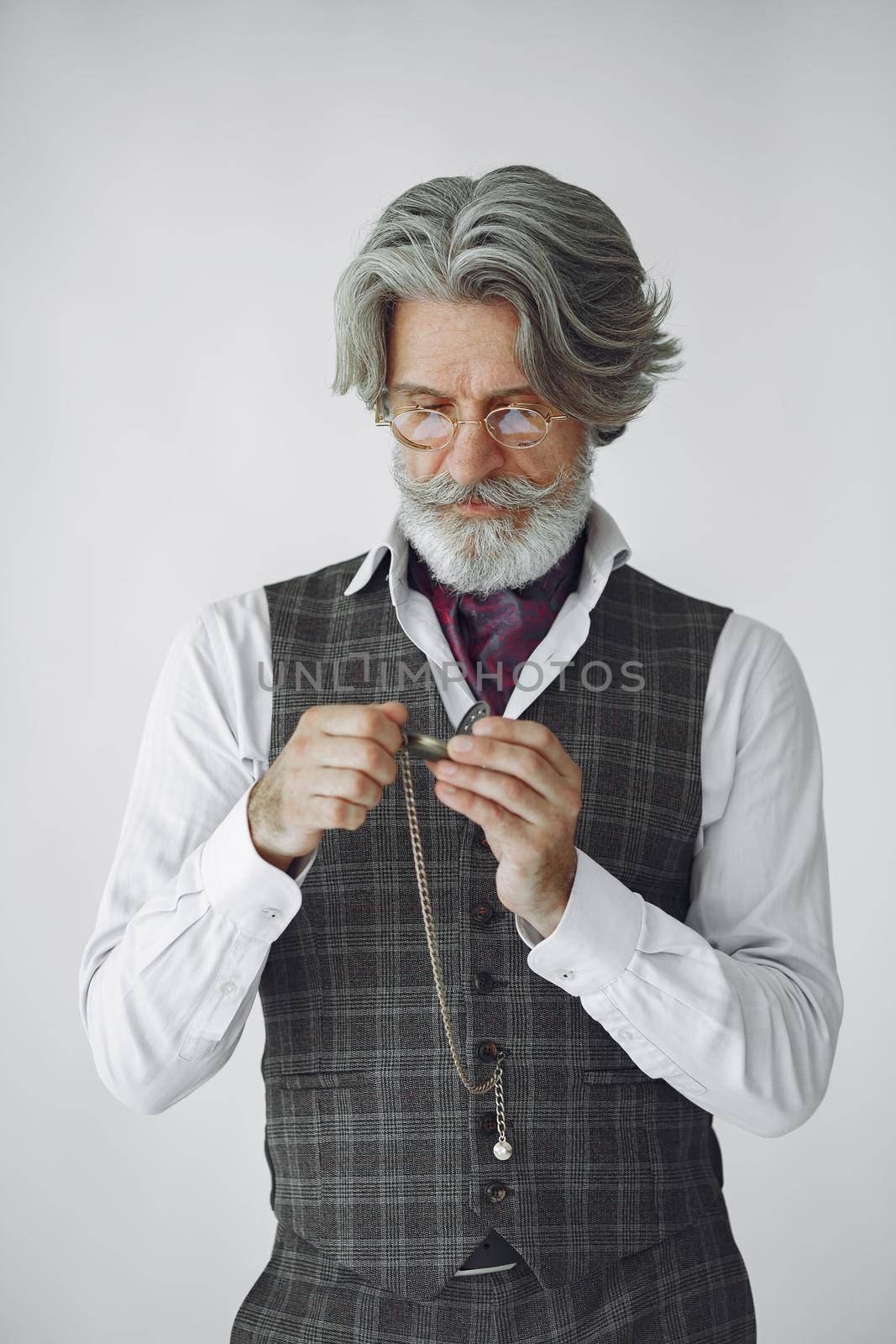 Close up portrait of grinning old-fashioned man. Elegant man in a studio. Grandfather with a clock.