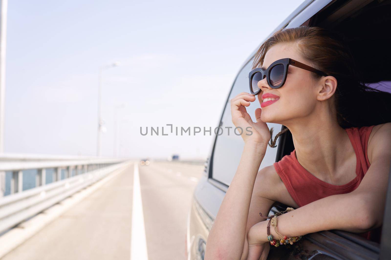 a woman is driving in a car on the road and looking out of the window. High quality photo
