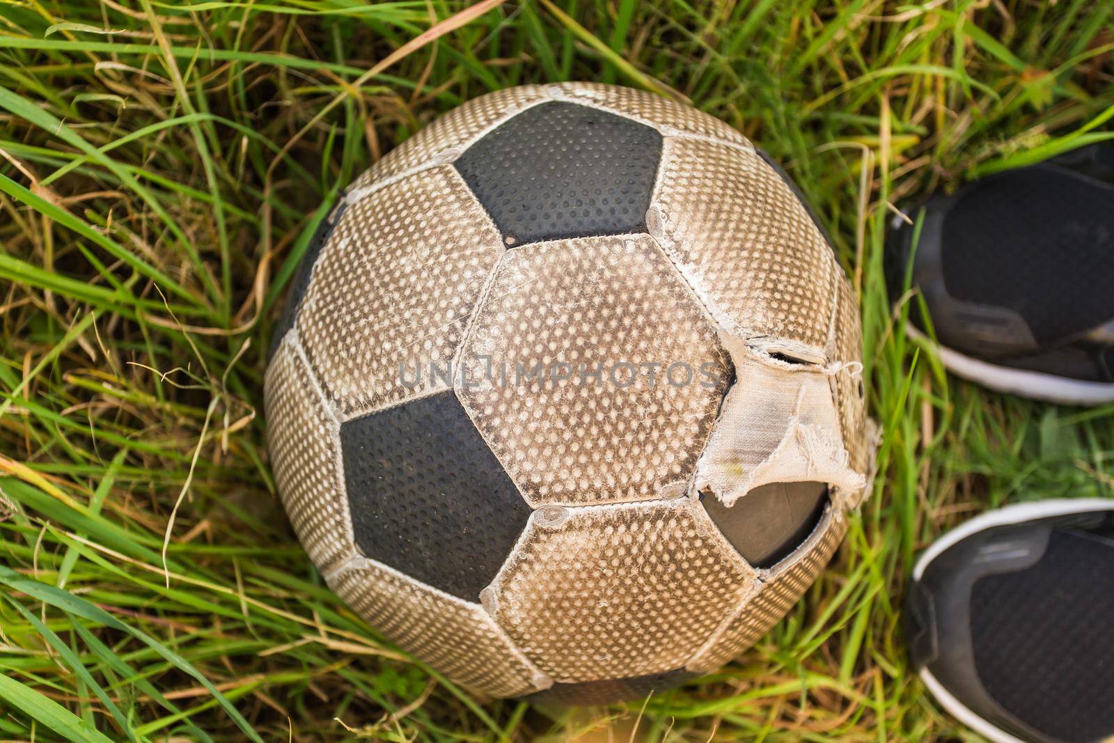 Old Soccer ball on the green grass, top view.