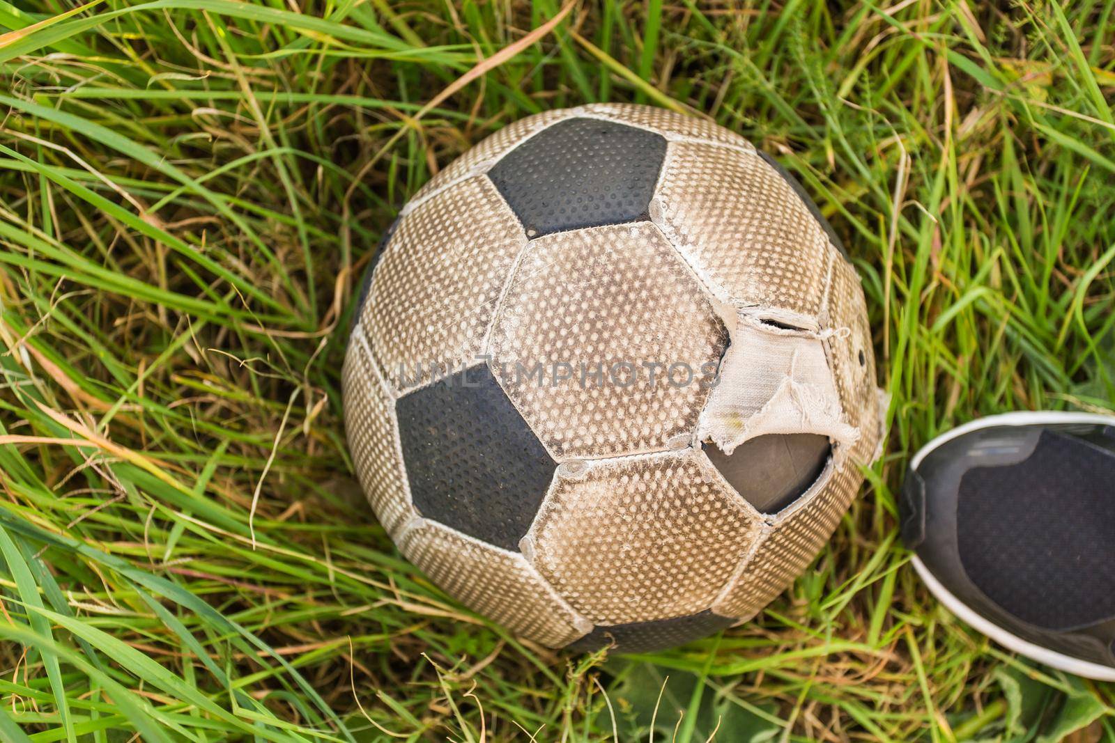 Old Soccer ball on the green grass, top view.