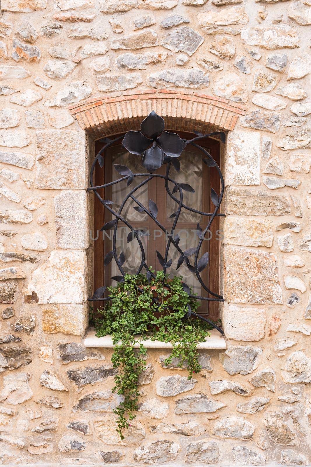 Design, architecture and exterior concept - Beautiful wrought-iron grille in the window on stone wall.