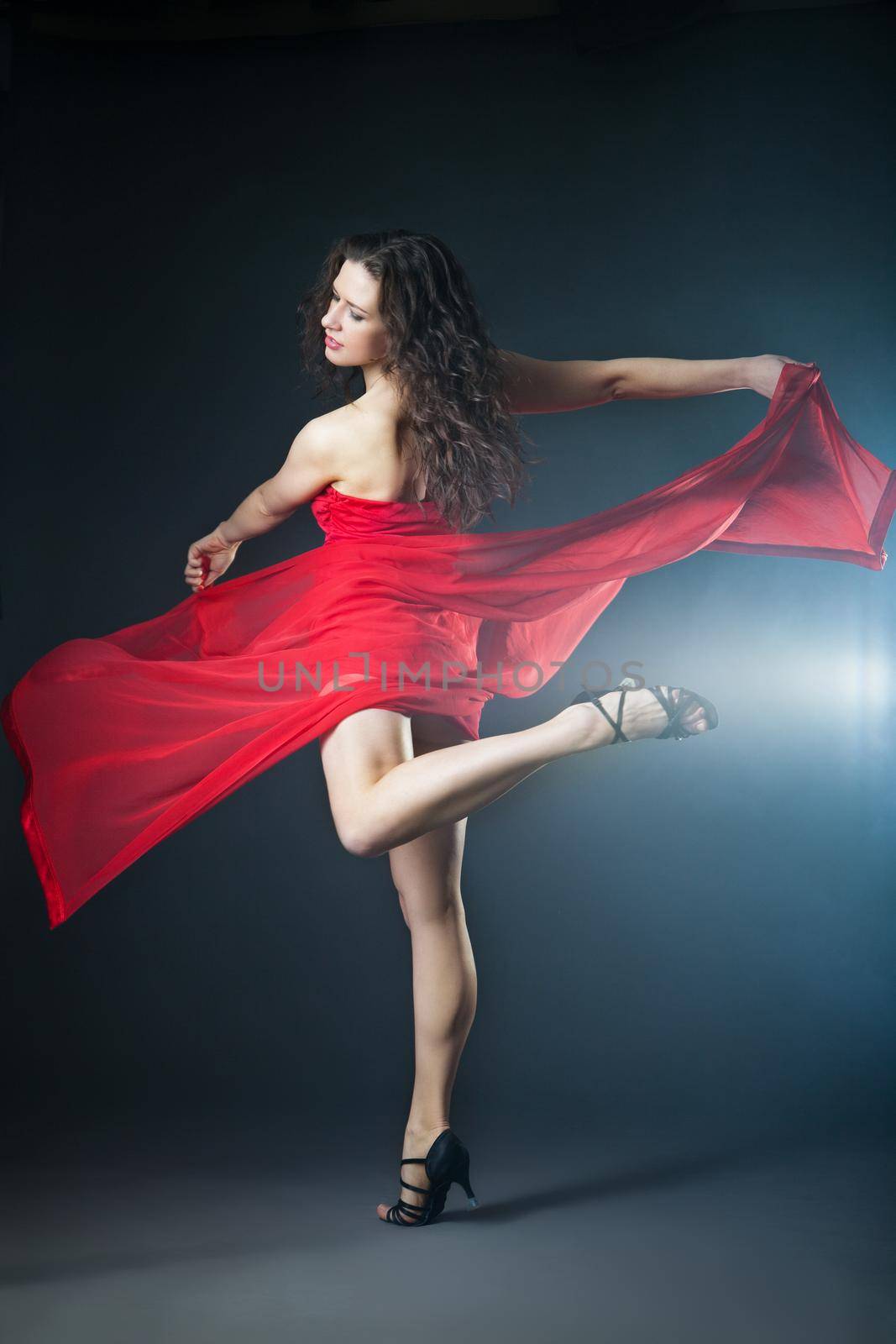 Young sexy dancing woman in red dress with fabric with smoke on background