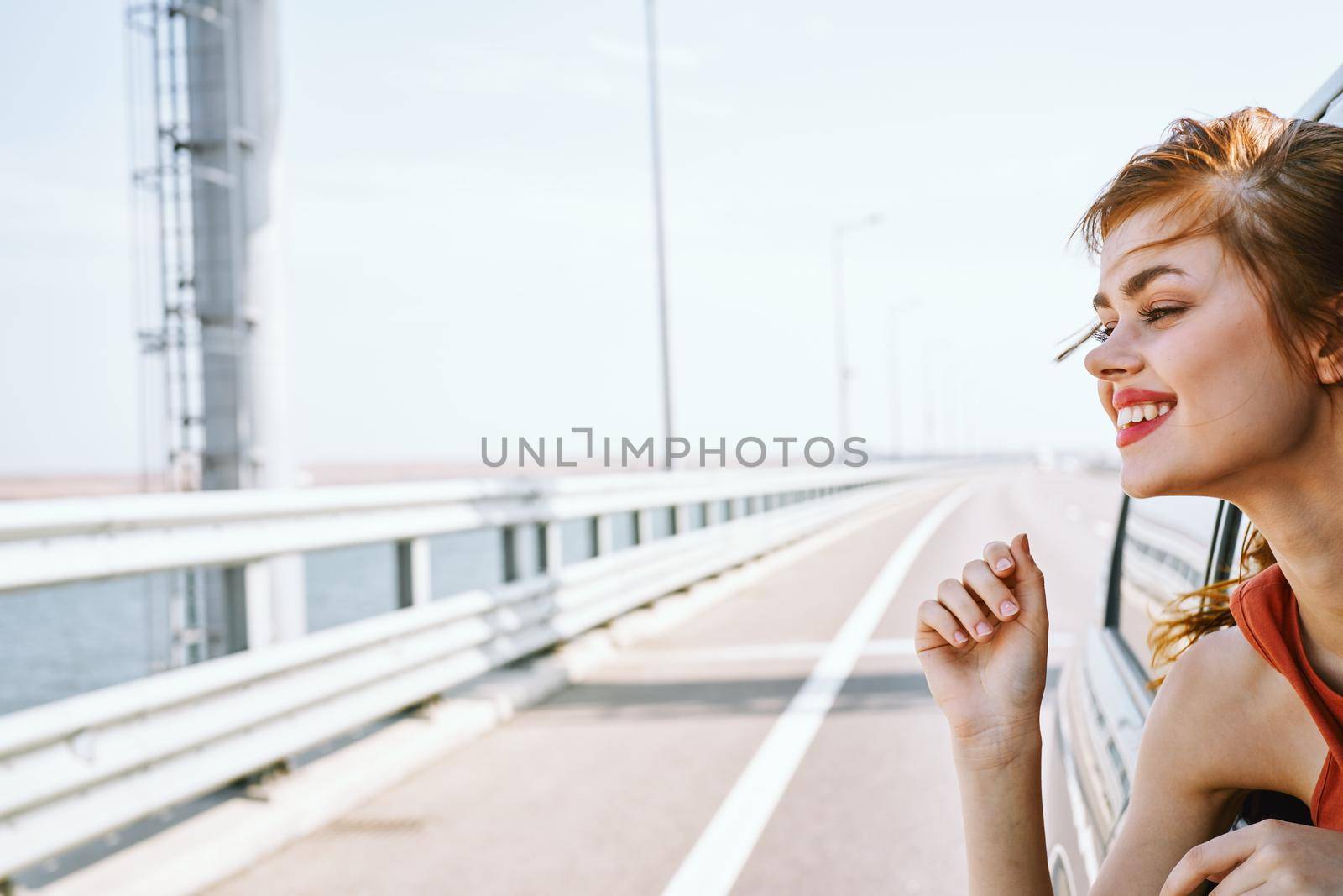 cheerful woman peeking out of the car window trip road travel. High quality photo