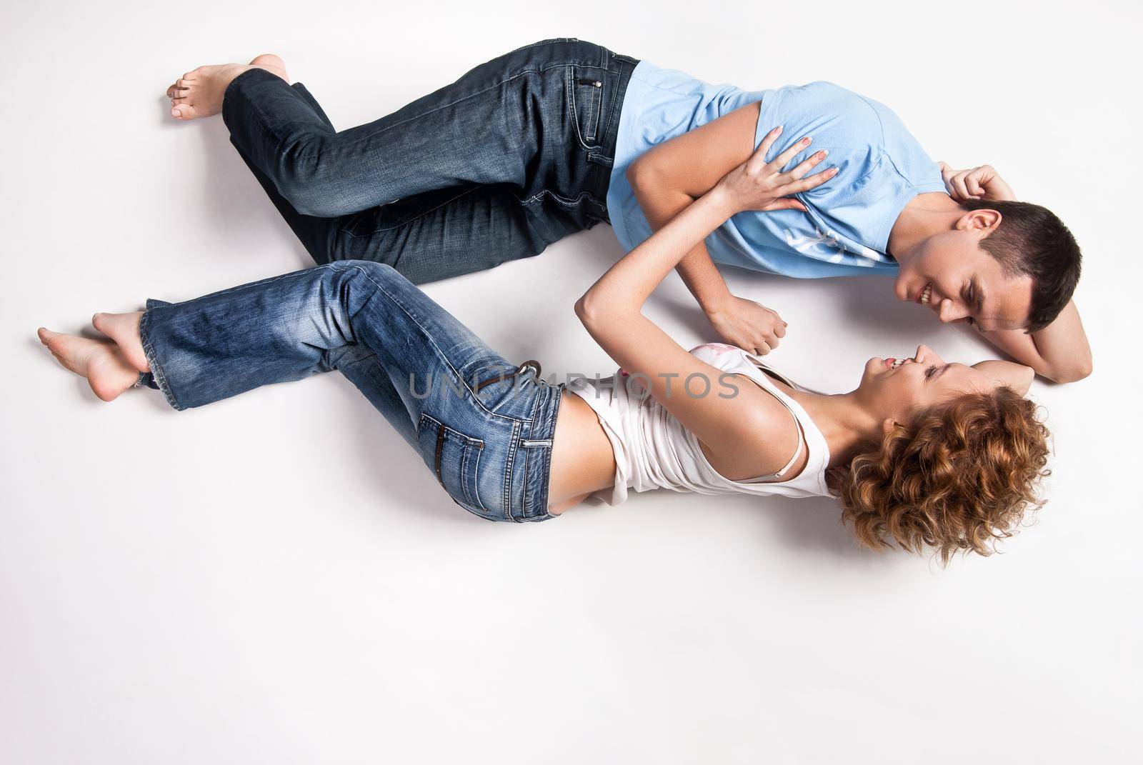 Portrait of a young happy couple lying on floor by Julenochek