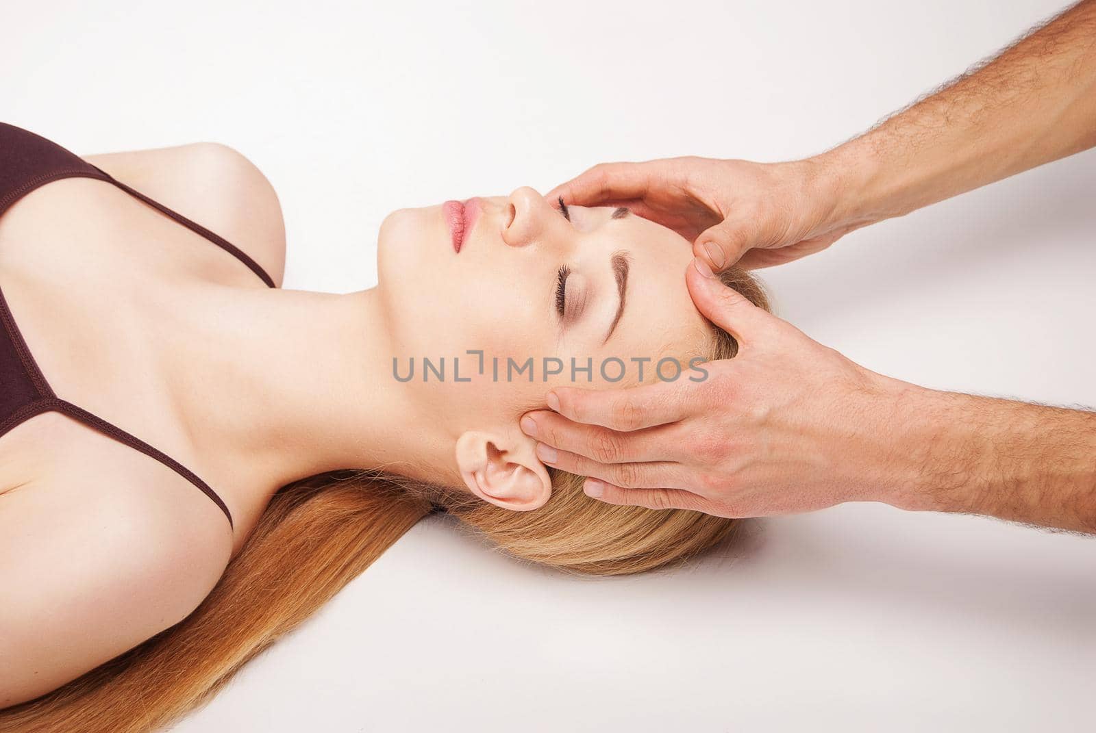 Young woman receiving a head massage on white by Julenochek