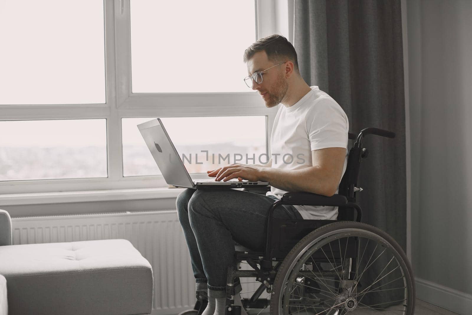 Disabled man using laptop. Cheerful handsome man stay at home and work remotely.