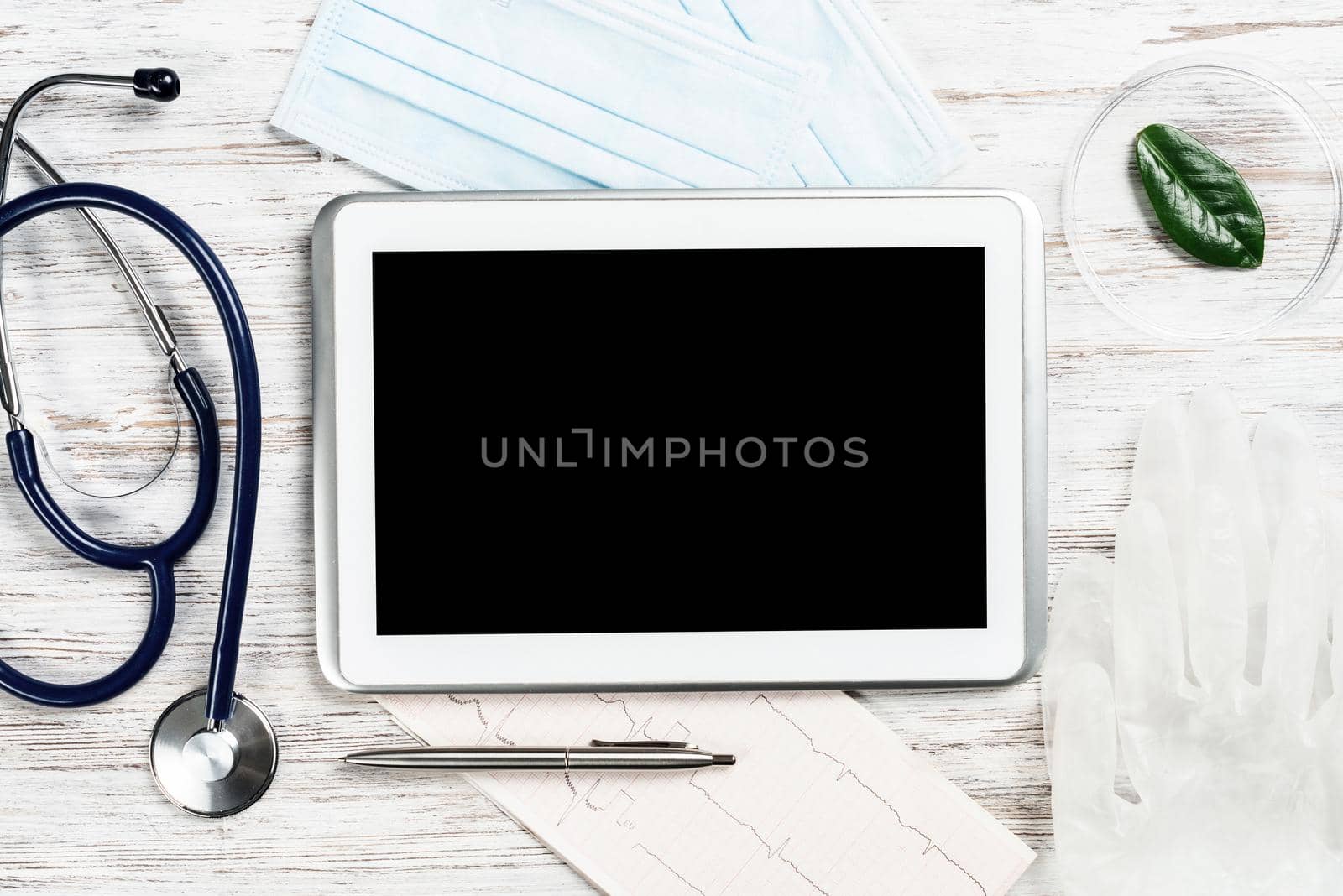 Laboratory patient examination in doctors office. Top view tablet computer, stethoscope and cardiogram on wooden desk. Medical diagnostics and examination in modern hospital. Healthcare technology