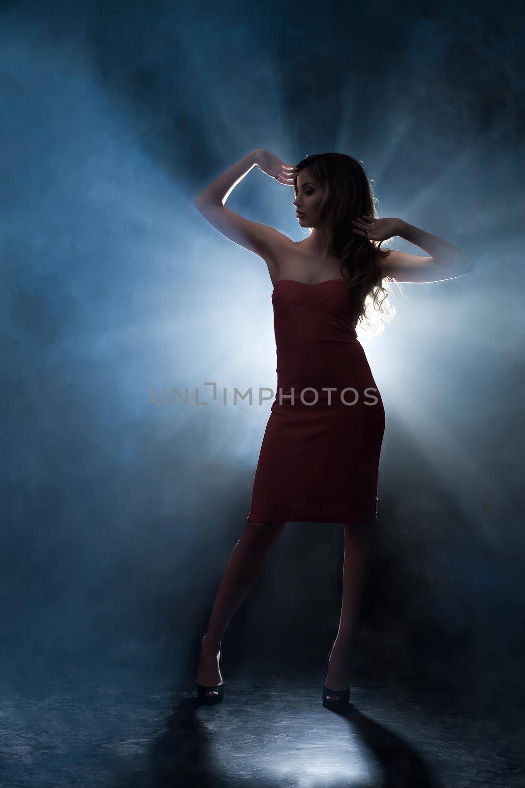 Portrait of a beautiful woman posing in a red dress in front of the scenes