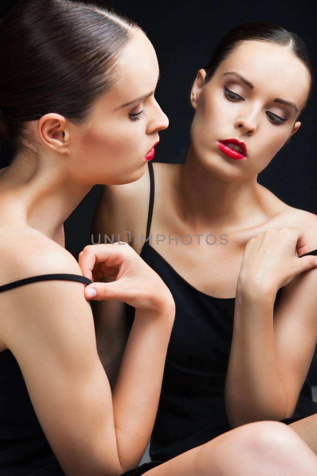 Beautiful sexy young woman near a mirror over black background