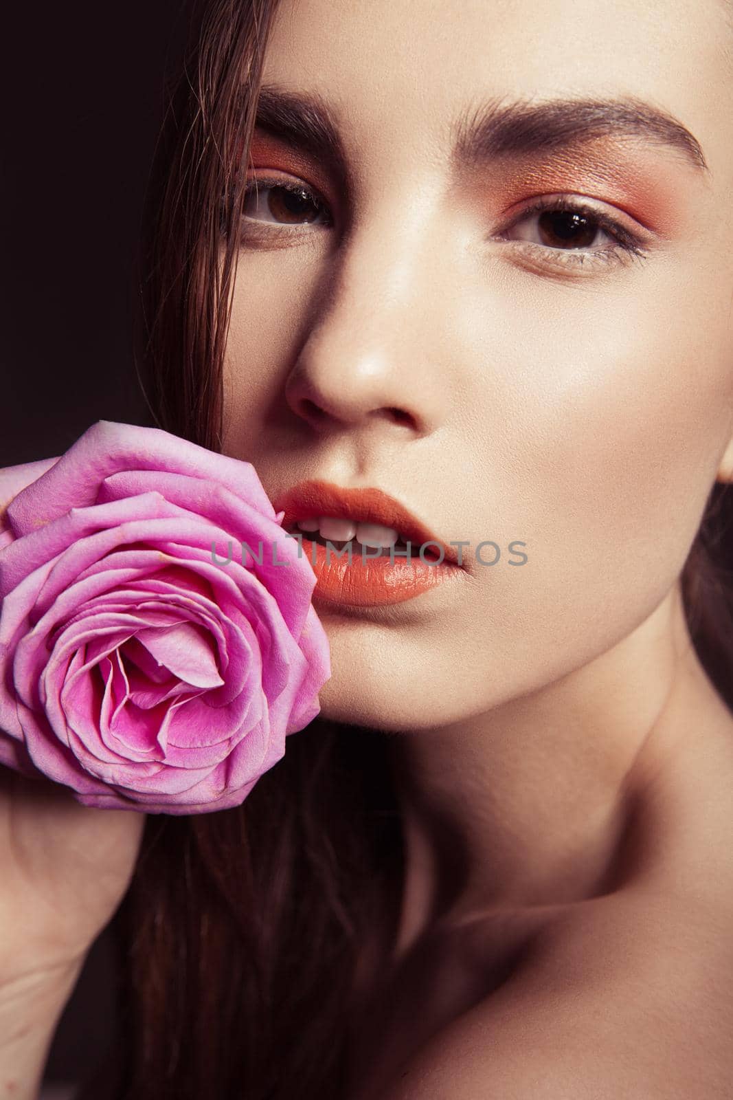 close-up portrait of beautiful brunette woman with pink rose