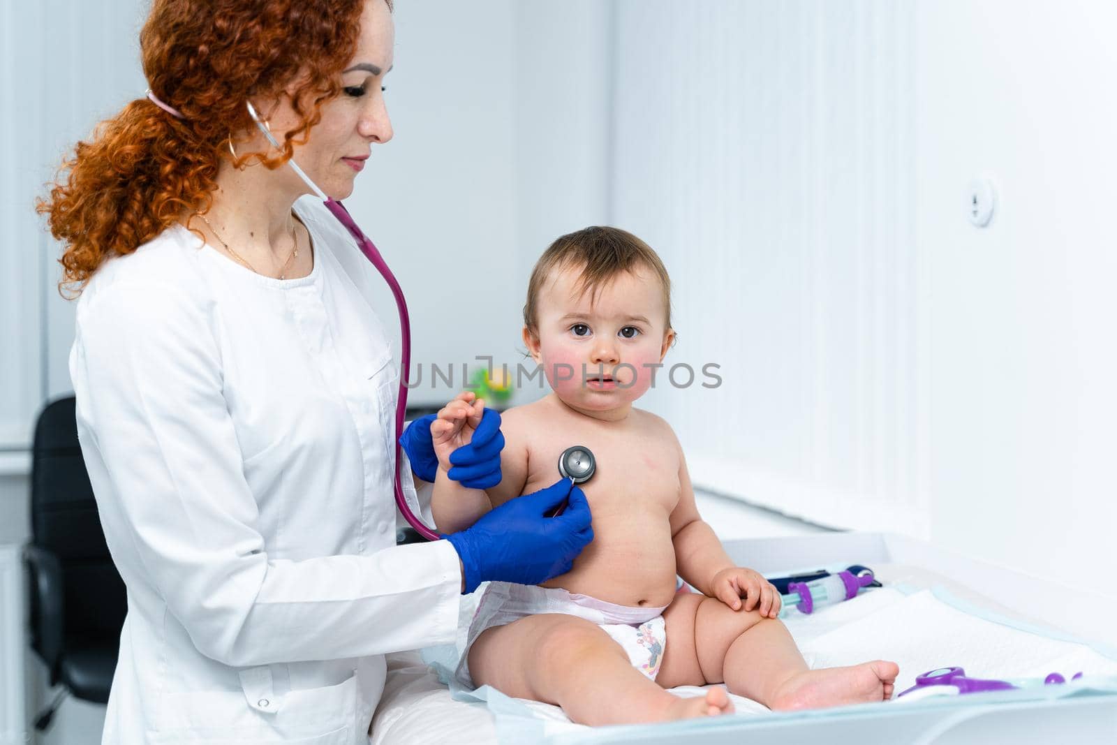 Pediatrician providing healthcare for her baby patient in the office of a specialized clinic for children. Neonatologist. Medical appointment little child one year old in the clinic. Health care of infant, children, kid.