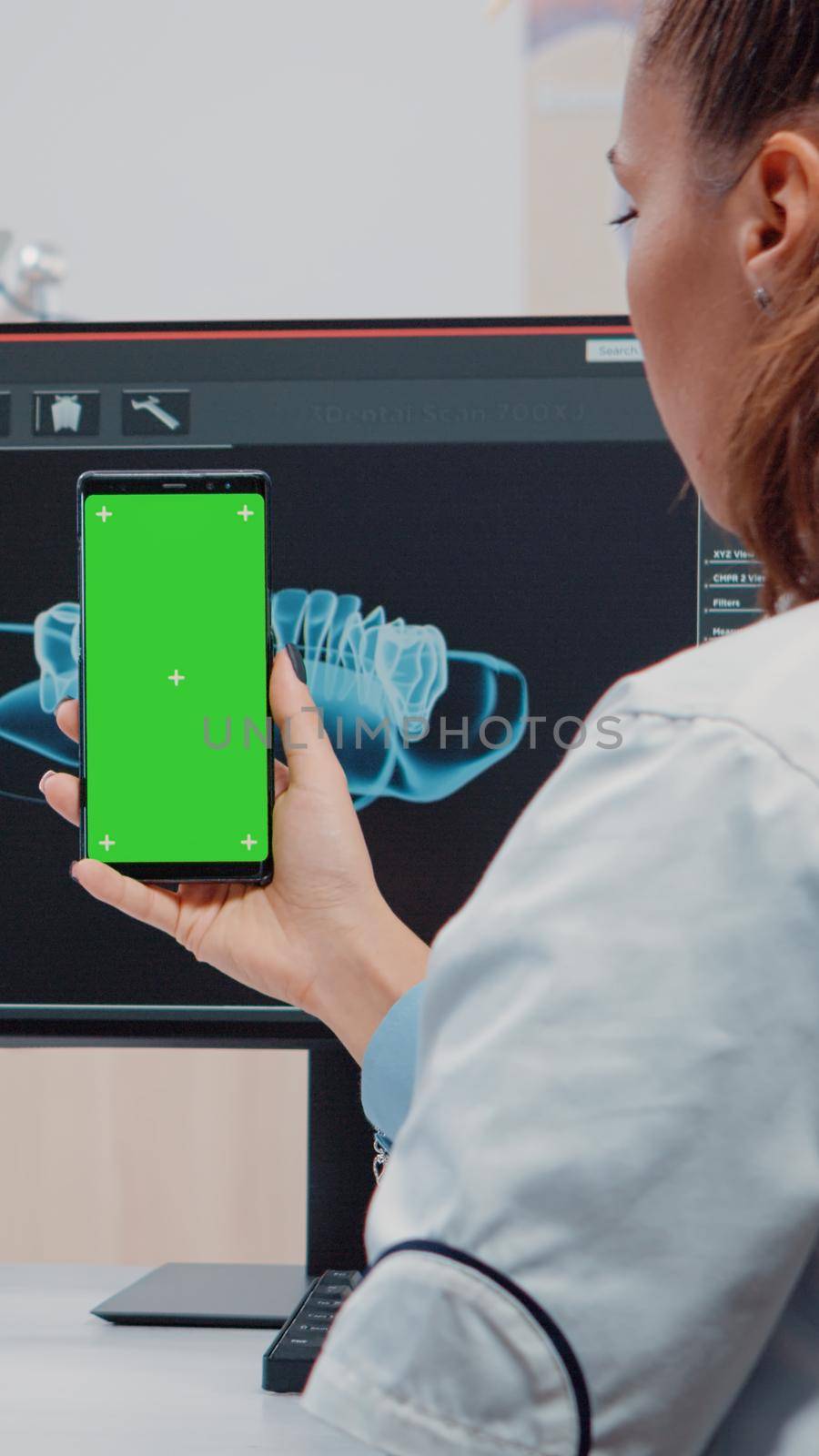 Dentist vertically holding smartphone with green screen by DCStudio