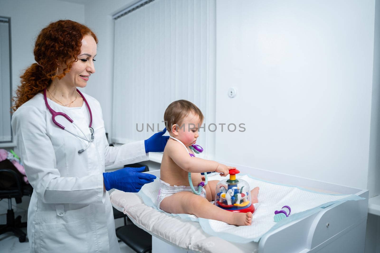 Pediatrician providing healthcare for her baby patient in the office of a specialized clinic for children. Neonatologist. Medical appointment little child one year old in the clinic. Health care of infant, children, kid.