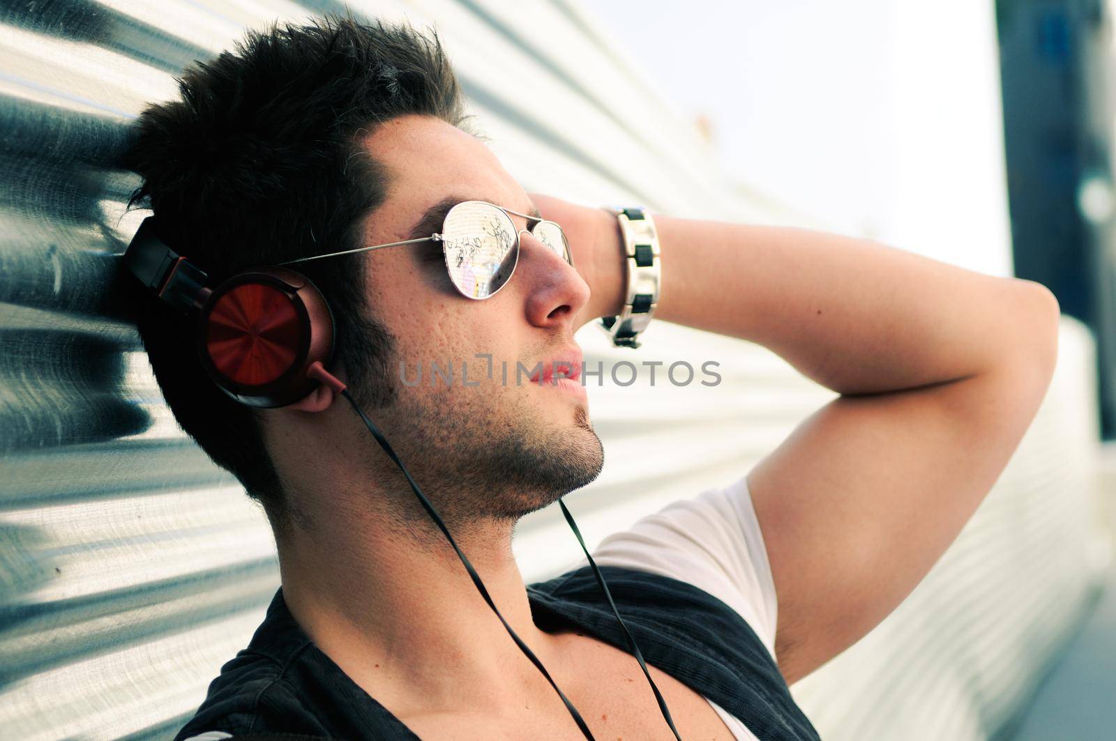 Portrait of handsome man in urban background listening to the music with headphones