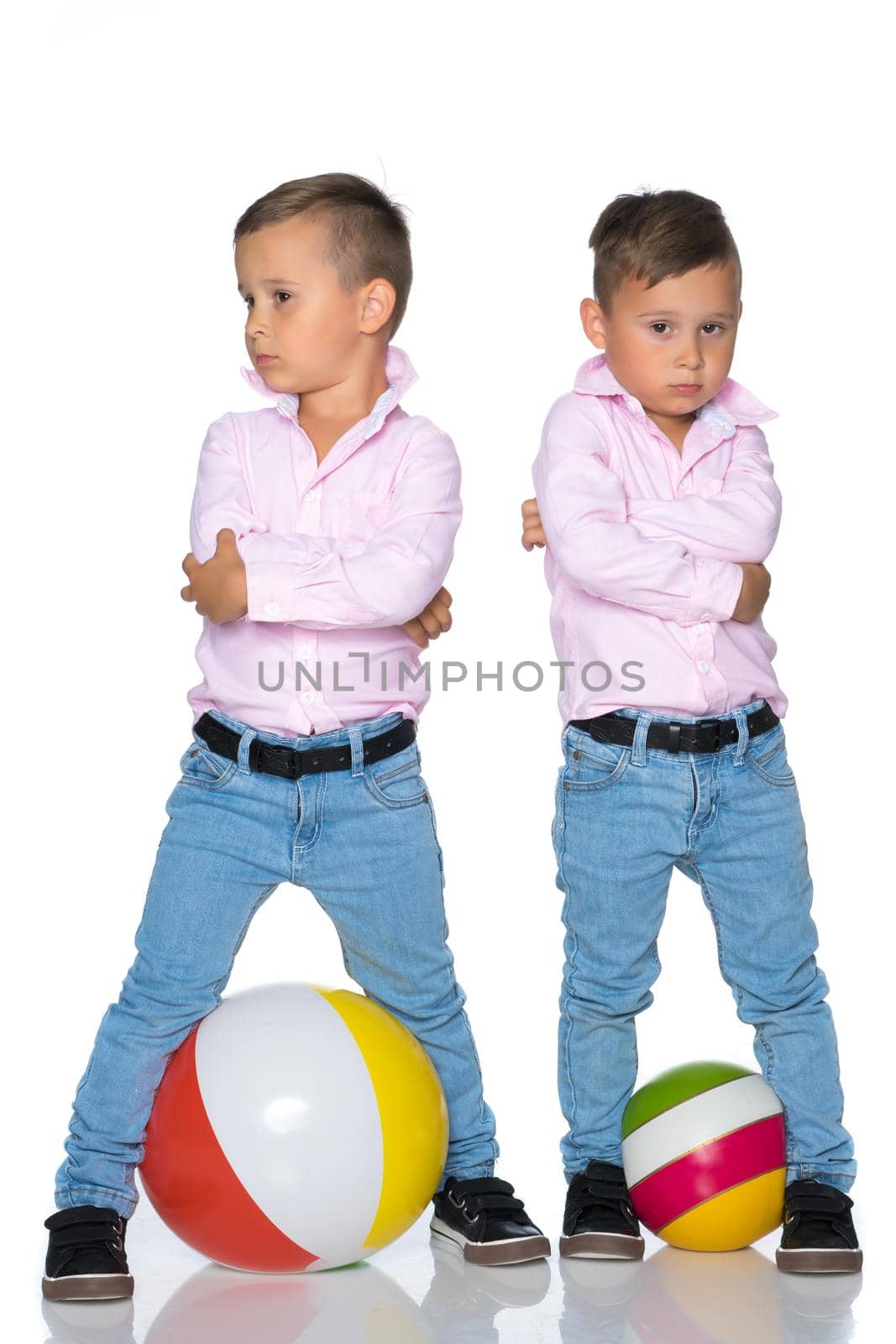 Two cute little boys stand in front of the camera in full growth. The concept of a happy childhood, the development of a child in the family. Isolated on white background.