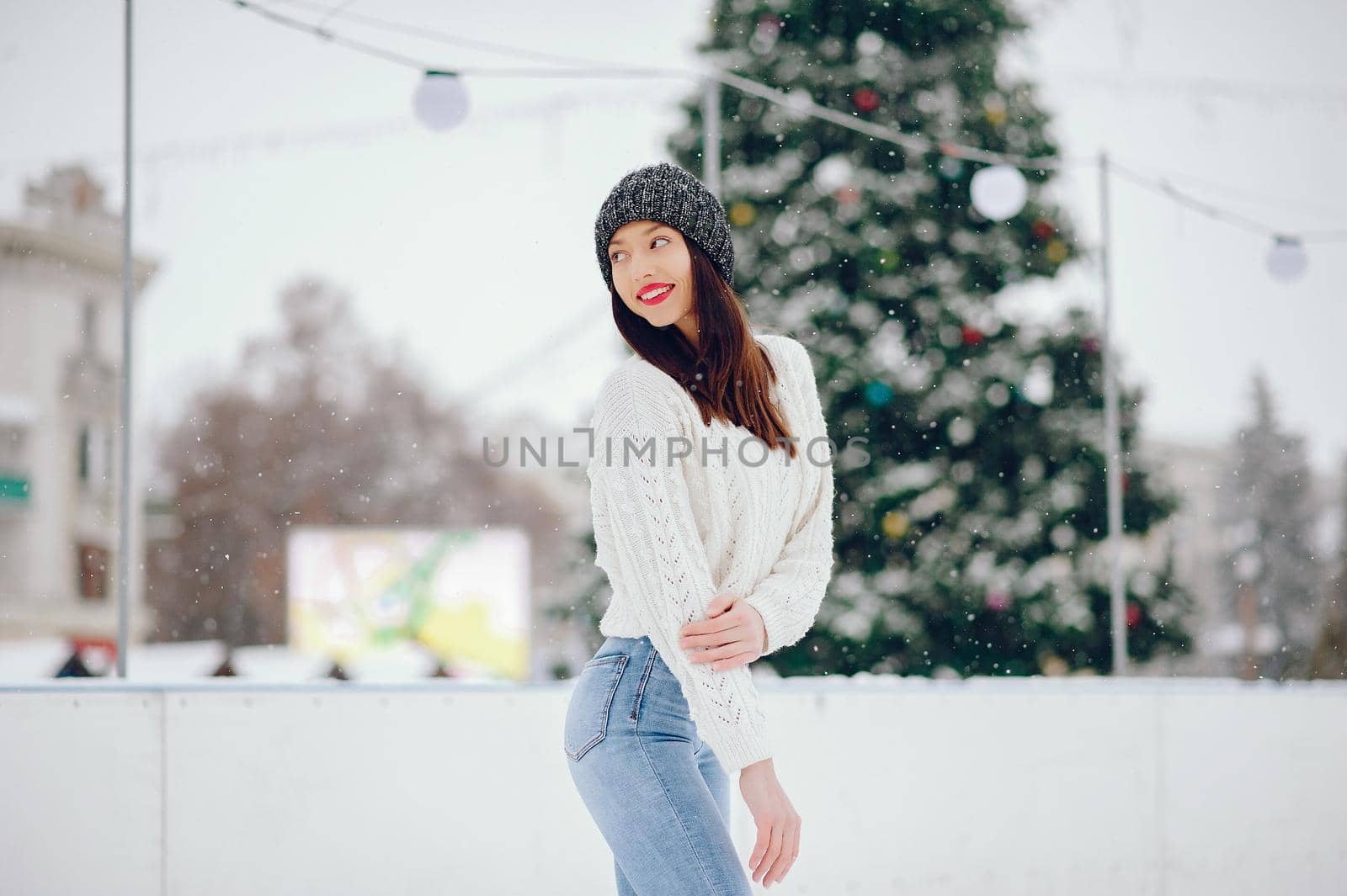 Cute girl standing in a winter city. Woman in a white sweater.