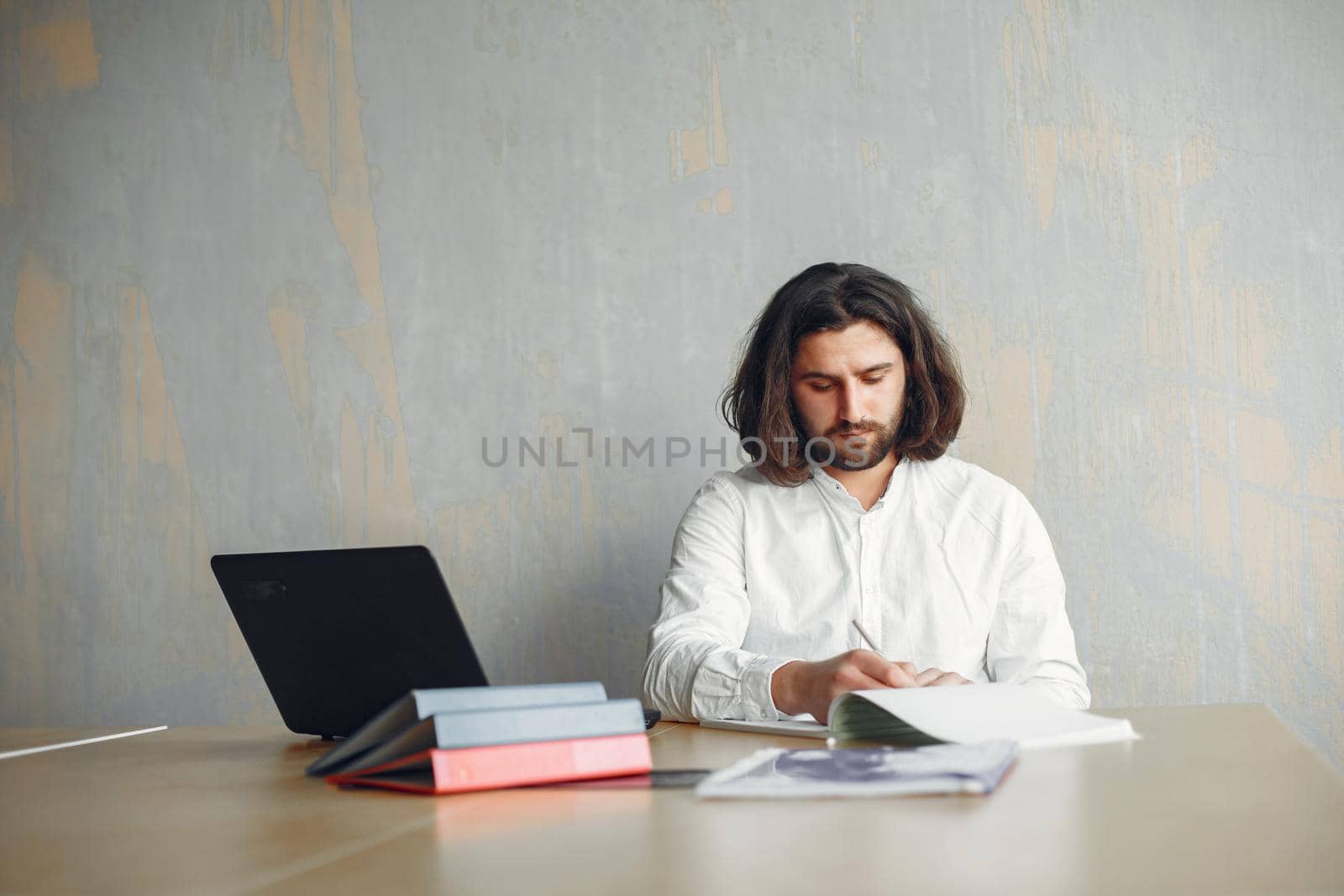 Handsome man in a white shirt. Businessman working at the office. Guy with a laptop.