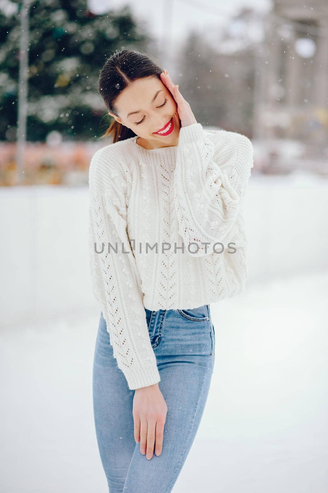 Cute girl standing in a winter city. Woman in a white sweater.