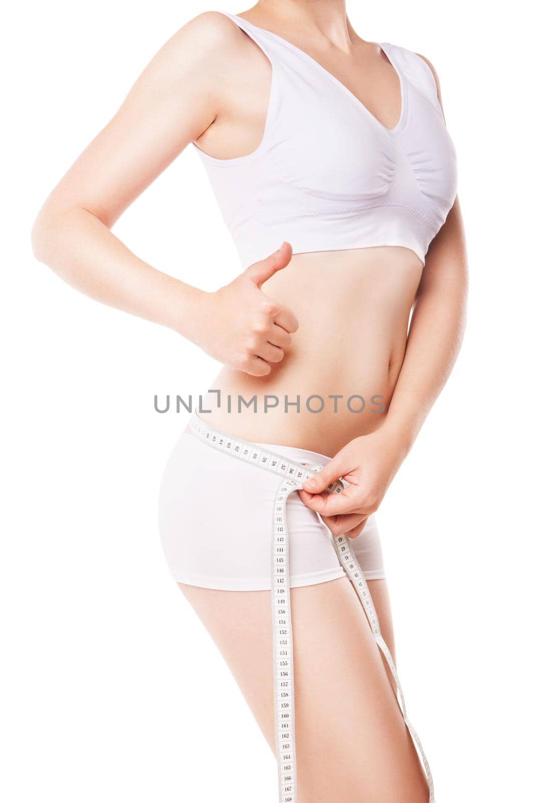 Athletic slim woman measuring her waist by measure tape after a diet and showing thumb up isolated over white background