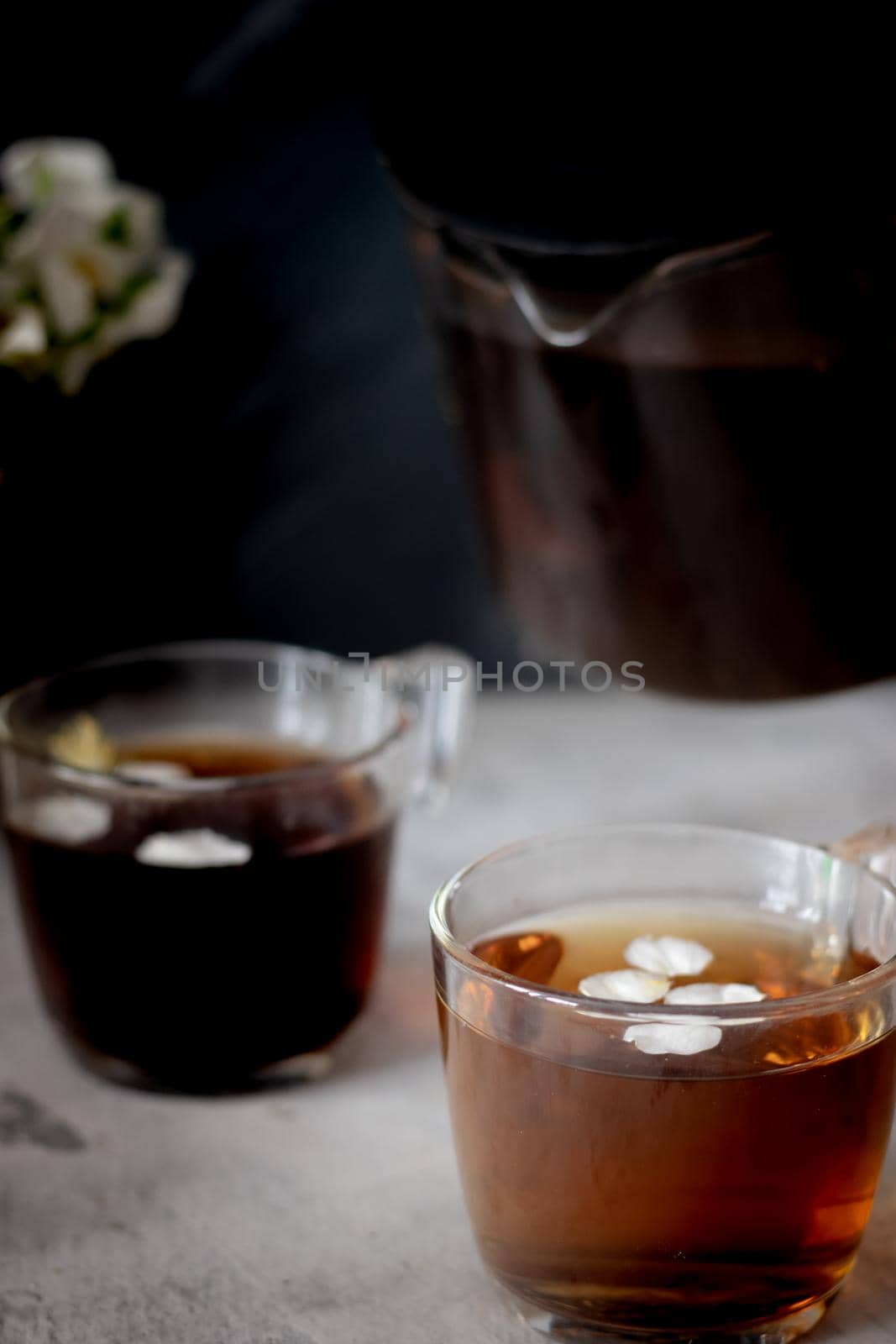 There is a teapot and two cups of black tea on the table. Dark mood, low key