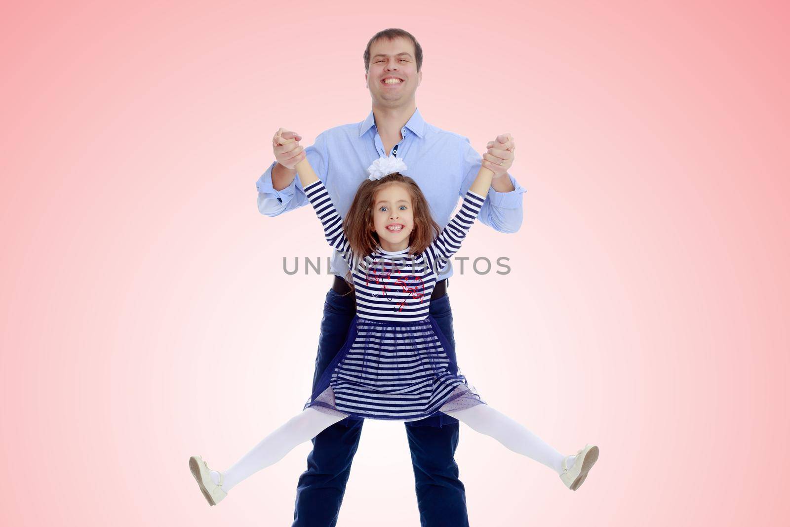 Happy young dad raise his beloved daughter's hands.Pale pink gradient background.