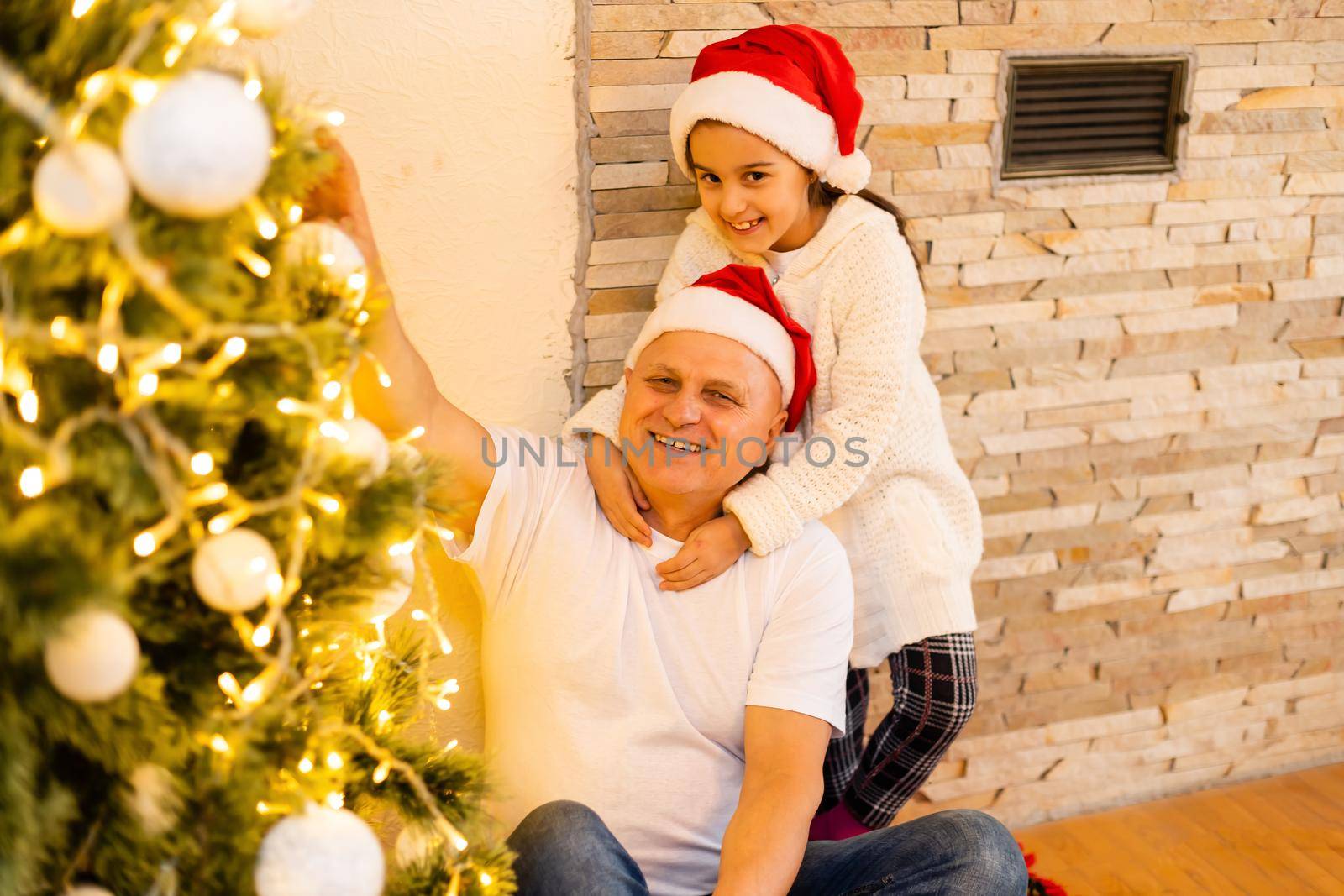 Little girl and her grandfather with Christmas gift at home by Andelov13