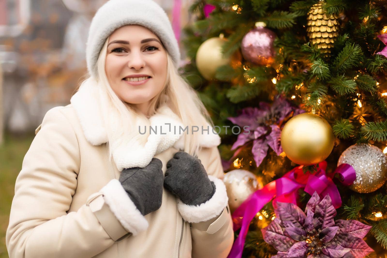 holidays and people concept - young woman in winter clothes over christmas tree