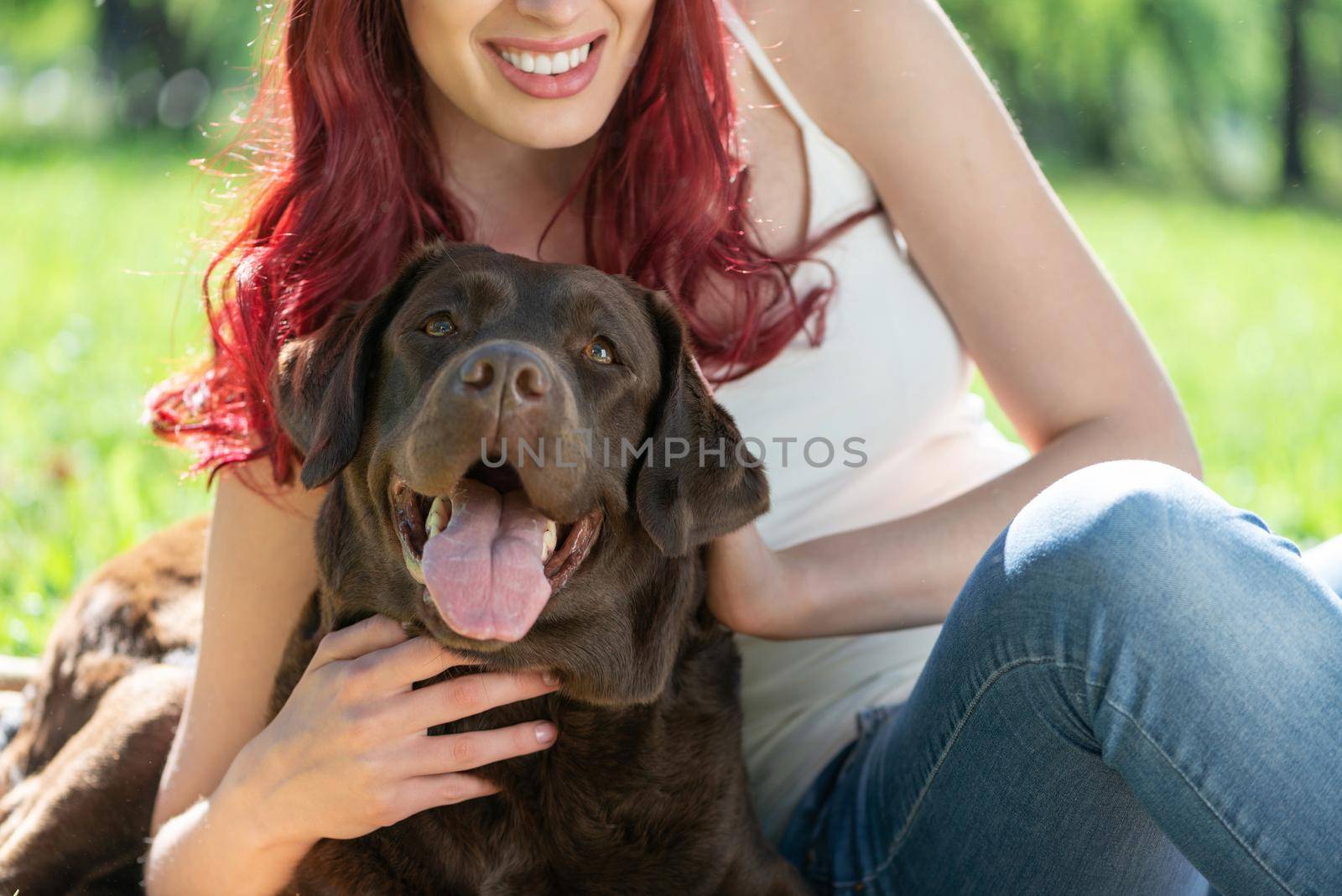 Young attractive woman hugs her dog in the park. by adam121