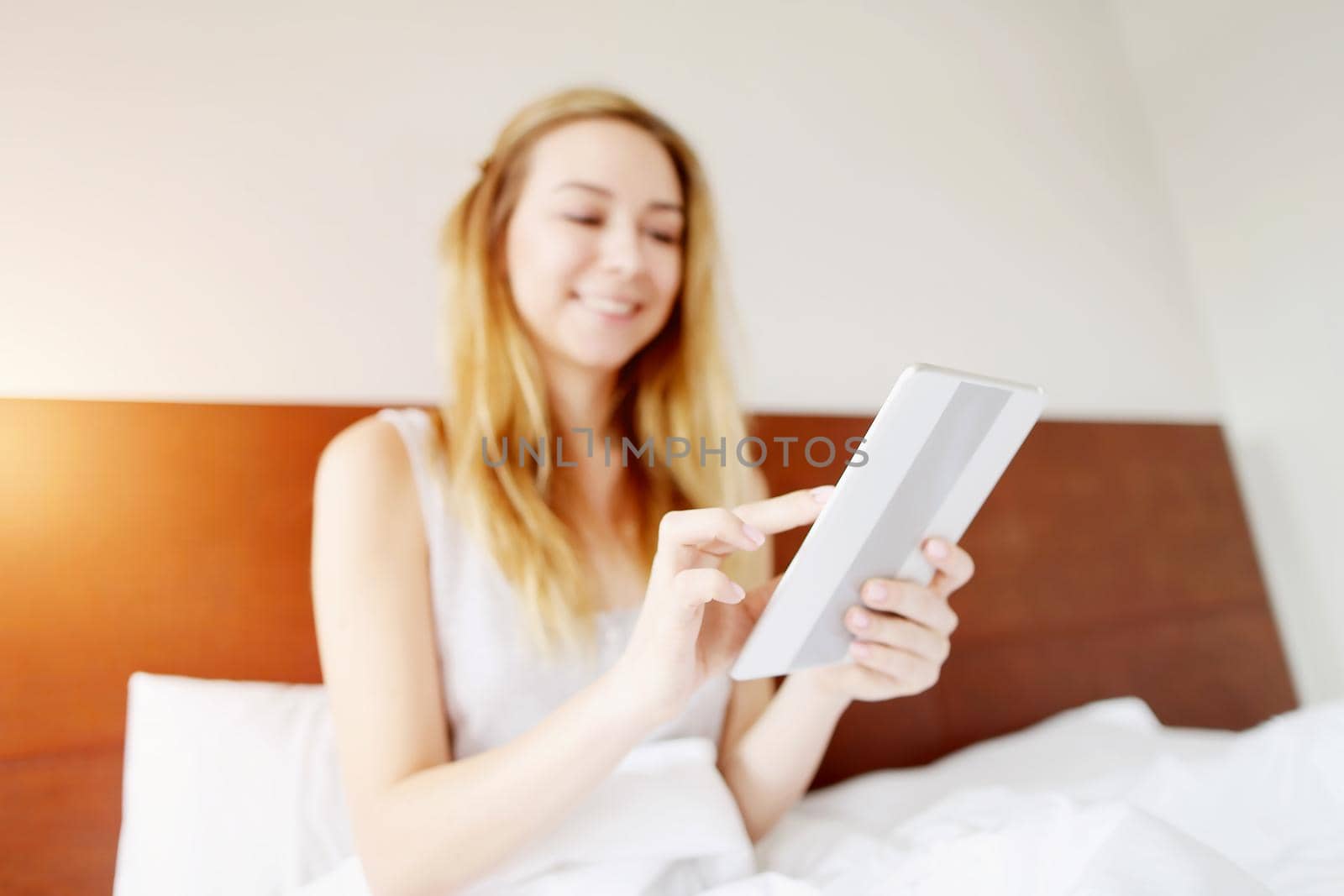 focus on tablet, european young woman working happy remotely at white bed by sisterspro