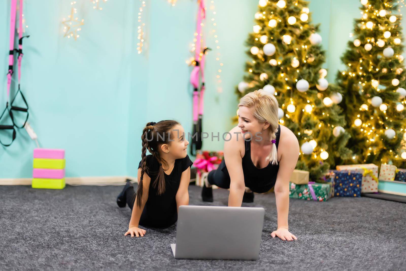 mother and daughter go in for sports near the christmas tree at home