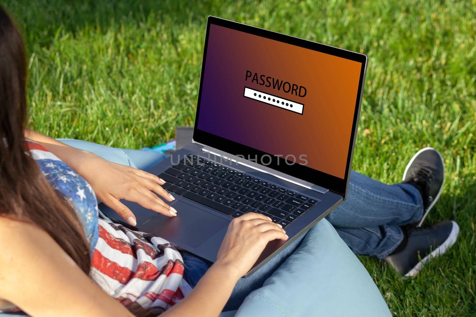 Close up hands on keyboard. Woman working on laptop pc computer with request password on screen, sitting in park on green grass sunshine lawn outdoors. Mobile Office. Freelance business concept